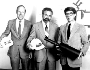 Hans Nyman, George Latimer, and John Taylor holding hard hats and pipe. 